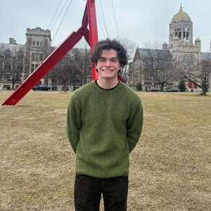 A college Student standing smiling in front of the Victor's Lament